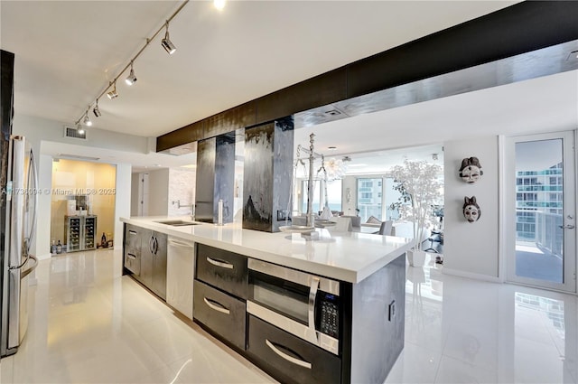 kitchen featuring track lighting, appliances with stainless steel finishes, a kitchen island with sink, and light tile patterned floors