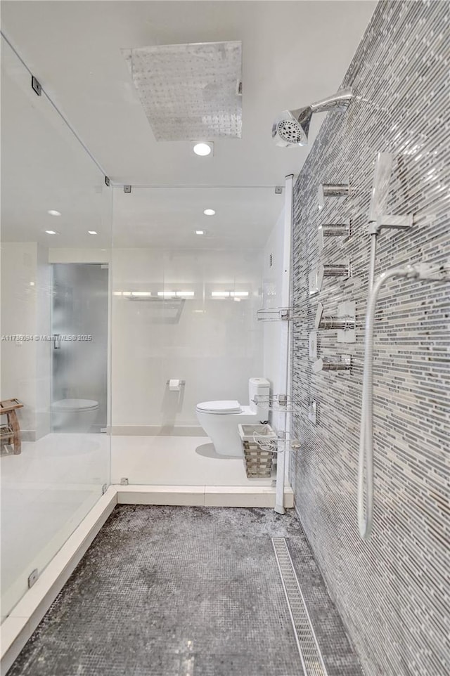 bathroom with toilet, tile walls, and a shower with shower door