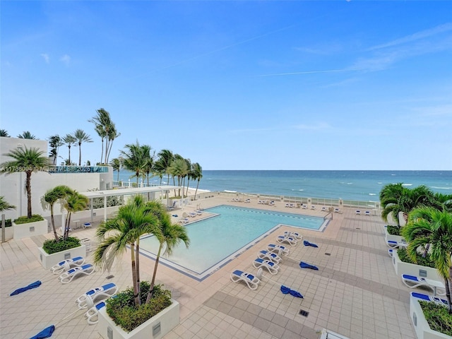 view of pool with a patio area, a beach view, and a water view