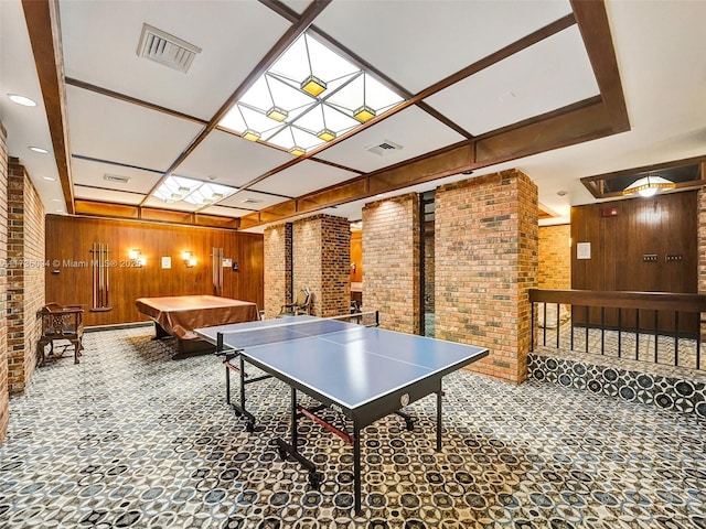 rec room with a skylight, wood walls, and brick wall