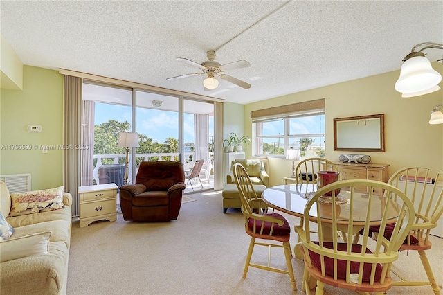 carpeted dining space featuring ceiling fan, a wall of windows, and a textured ceiling