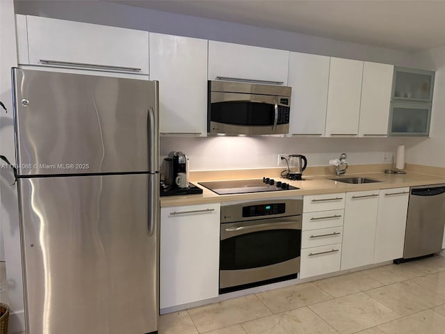 kitchen with white cabinetry, appliances with stainless steel finishes, sink, and light tile patterned floors