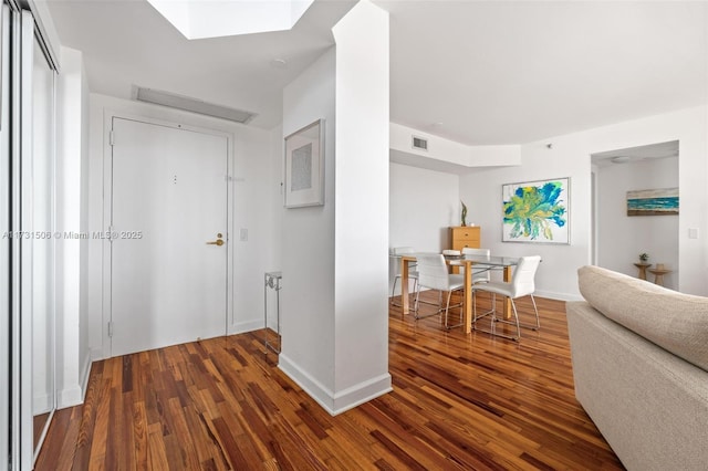 corridor featuring dark hardwood / wood-style floors and a skylight