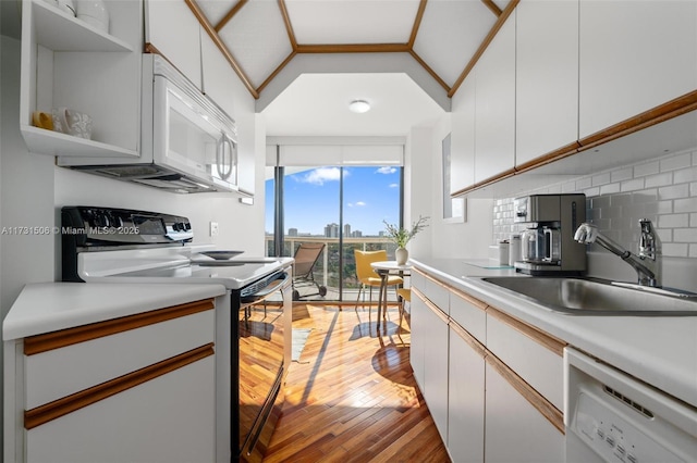 kitchen featuring sink, tasteful backsplash, white appliances, light hardwood / wood-style floors, and white cabinets