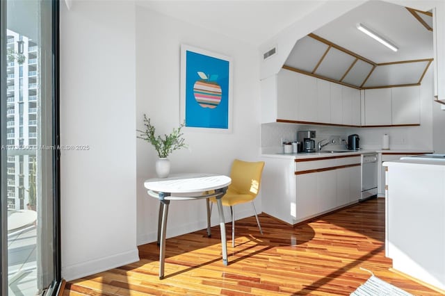 kitchen featuring lofted ceiling, sink, white cabinetry, light hardwood / wood-style flooring, and white dishwasher