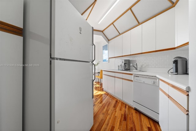 kitchen featuring sink, white cabinetry, white appliances, light hardwood / wood-style floors, and decorative backsplash