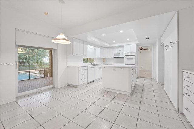 kitchen with sink, a kitchen island, pendant lighting, white appliances, and white cabinets