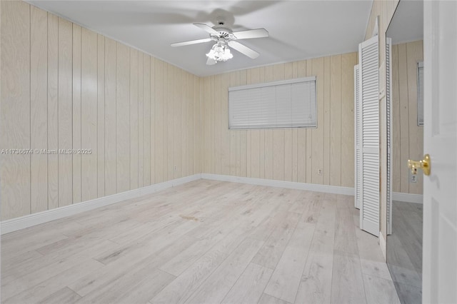 interior space featuring ceiling fan, wooden walls, and light hardwood / wood-style flooring