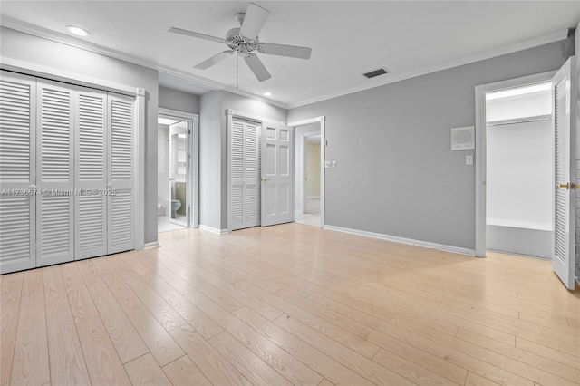 unfurnished bedroom with ceiling fan, connected bathroom, ornamental molding, light hardwood / wood-style floors, and two closets