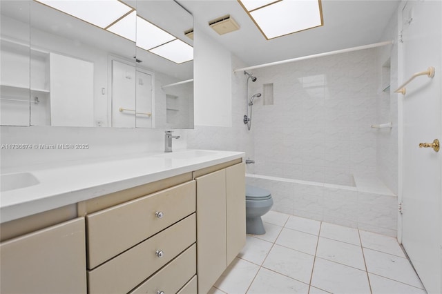 full bathroom featuring tile patterned flooring, vanity, tiled shower / bath, and toilet