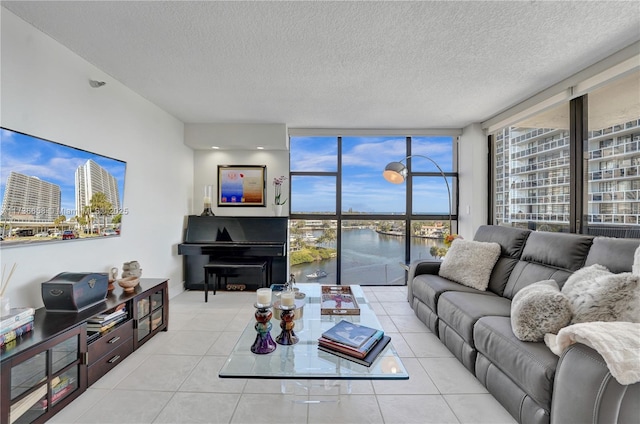 living room with a textured ceiling, floor to ceiling windows, a water view, and light tile patterned floors