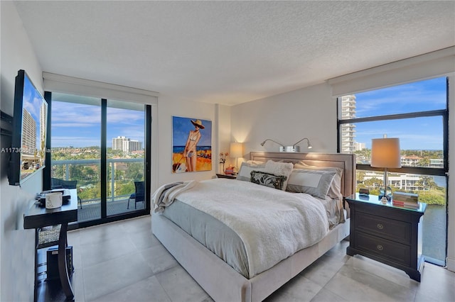 bedroom featuring expansive windows, access to exterior, and a textured ceiling