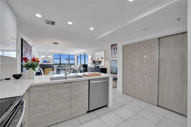 kitchen with light tile patterned floors, sink, stainless steel appliances, and kitchen peninsula
