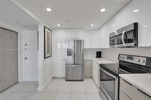 kitchen with white cabinetry, light tile patterned flooring, tasteful backsplash, and stainless steel appliances