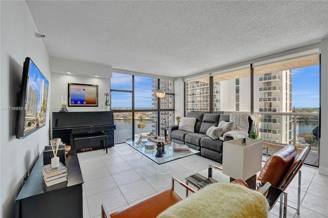 living room with a wall of windows, a water view, light tile patterned flooring, and a textured ceiling