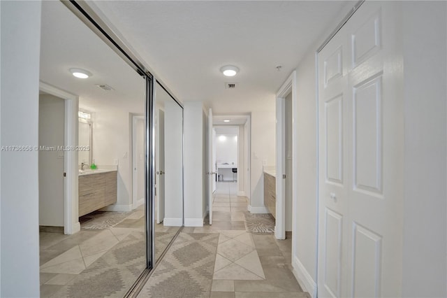 hallway featuring sink and light tile patterned floors