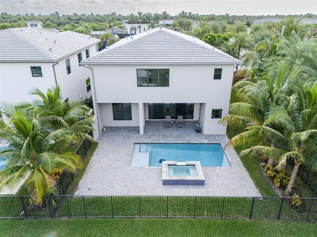 rear view of property featuring a swimming pool with hot tub and a patio area