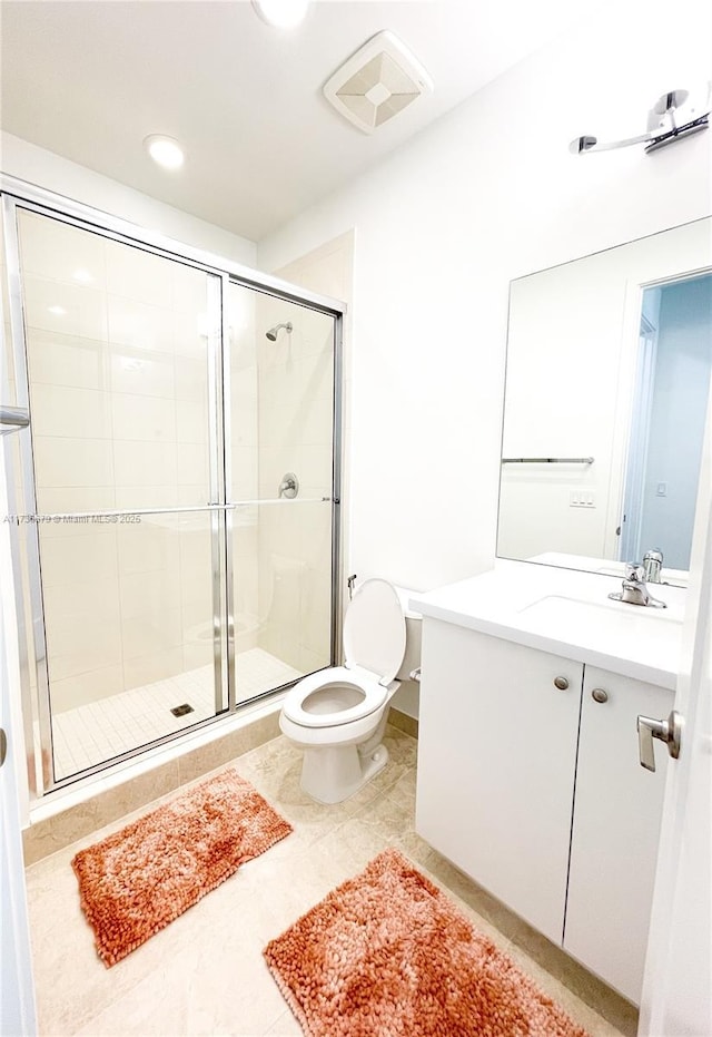 bathroom featuring vanity, tile patterned flooring, a shower with shower door, and toilet