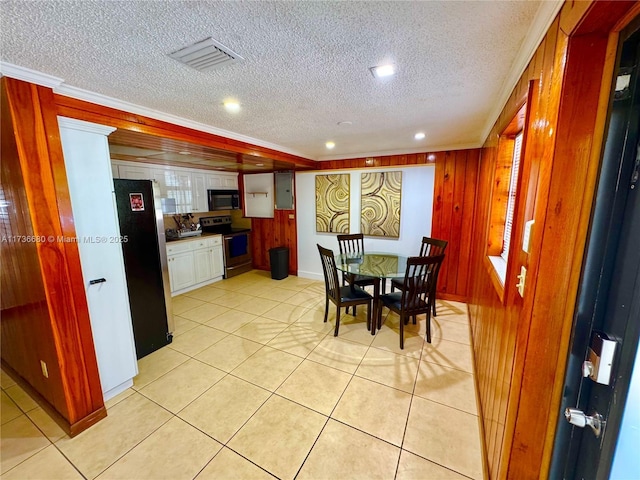 tiled dining area featuring wooden walls, ornamental molding, a textured ceiling, and electric panel