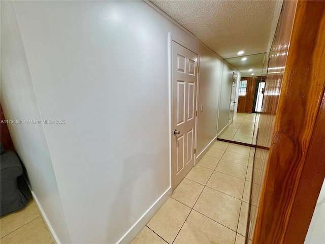 corridor featuring a textured ceiling and light tile patterned floors