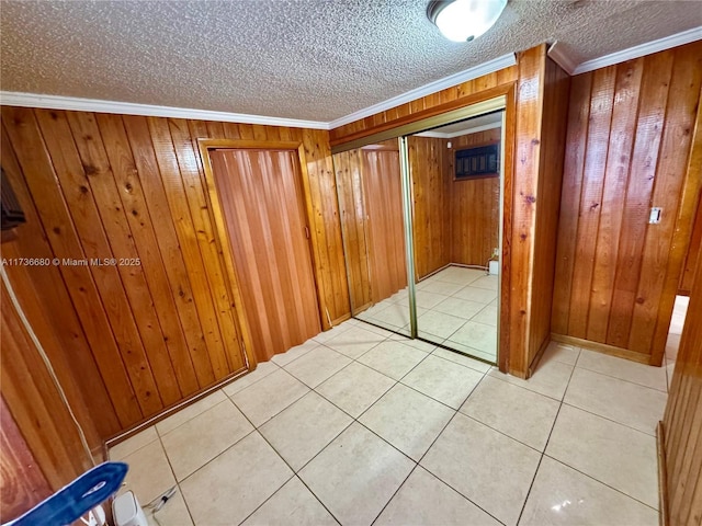 hall featuring crown molding, light tile patterned flooring, a textured ceiling, and wood walls