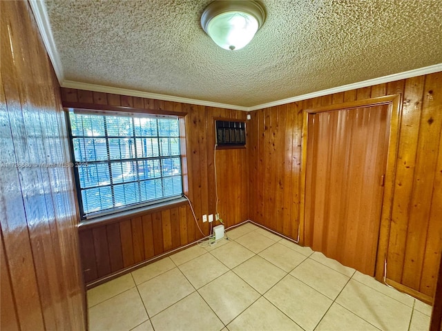 spare room with ornamental molding, wooden walls, and a textured ceiling