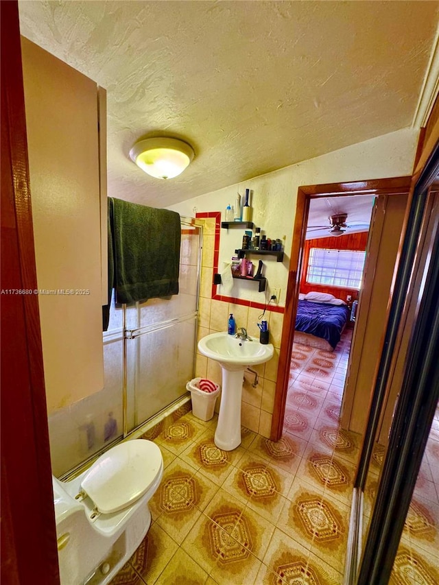 bathroom with toilet, sink, vaulted ceiling, a textured ceiling, and tile patterned flooring