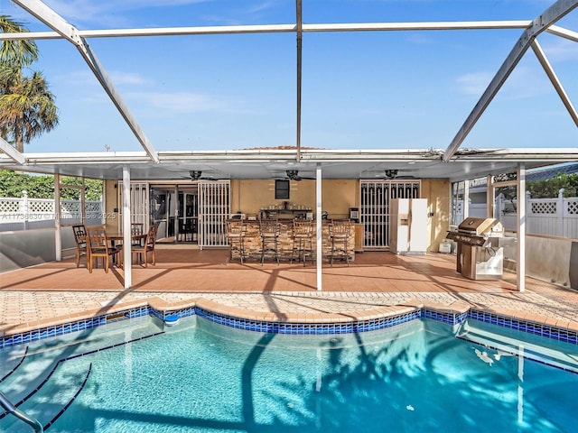 view of pool with a lanai, ceiling fan, a grill, a patio area, and exterior bar