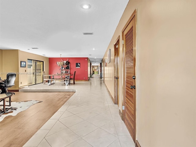 hall featuring light tile patterned floors, baseboards, and visible vents