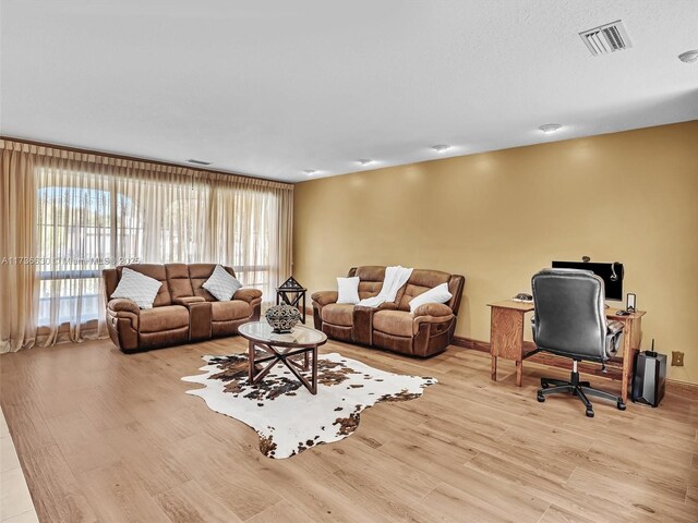 living room featuring light wood-style flooring, visible vents, and baseboards