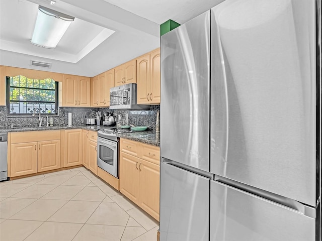 kitchen featuring stainless steel appliances, tasteful backsplash, visible vents, light brown cabinets, and a sink