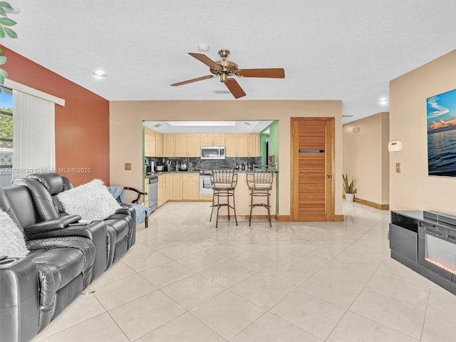 living area featuring ceiling fan, baseboards, and light tile patterned floors