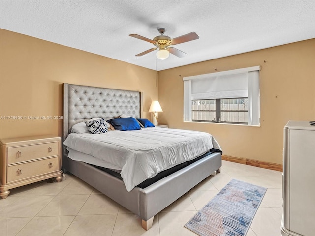 bedroom with a textured ceiling, light tile patterned flooring, a ceiling fan, and baseboards