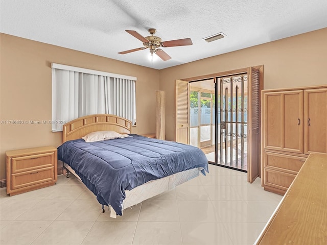 bedroom featuring light tile patterned floors, visible vents, ceiling fan, access to outside, and a textured ceiling