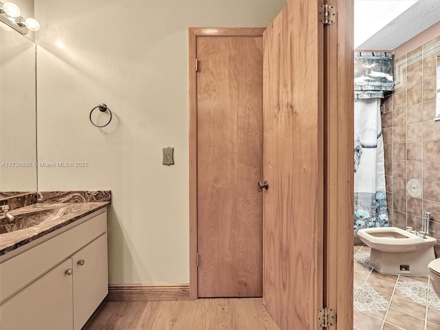 bathroom with wood finished floors, vanity, toilet, and baseboards