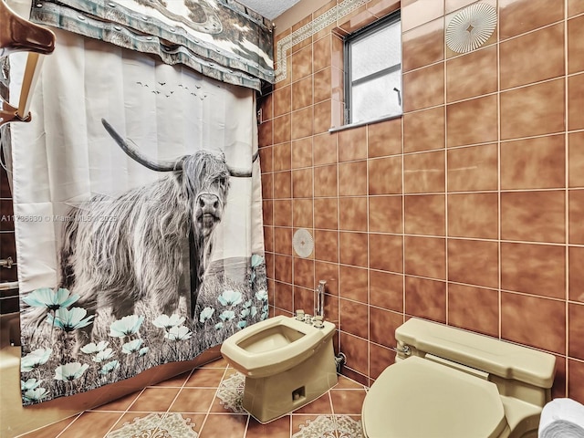 bathroom with toilet, a shower with curtain, tile patterned flooring, a bidet, and tile walls