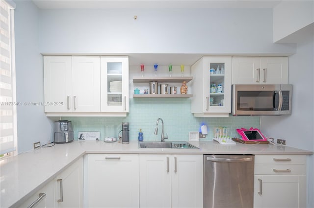 kitchen with white cabinetry, appliances with stainless steel finishes, sink, and backsplash