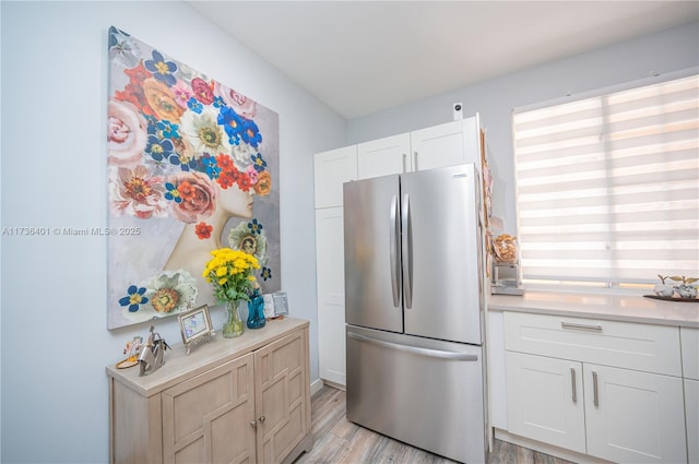 kitchen with white cabinetry, light wood-type flooring, and stainless steel refrigerator