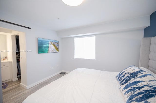 bedroom with a barn door and light wood-type flooring