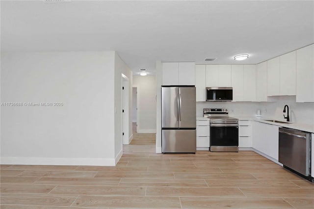 kitchen featuring white cabinetry, appliances with stainless steel finishes, sink, and decorative backsplash