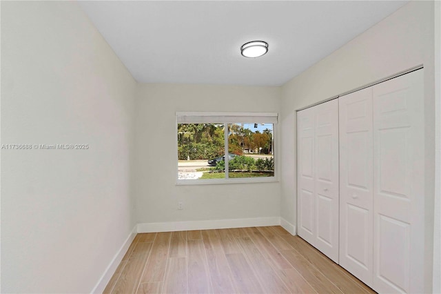 unfurnished bedroom featuring light wood-type flooring and a closet