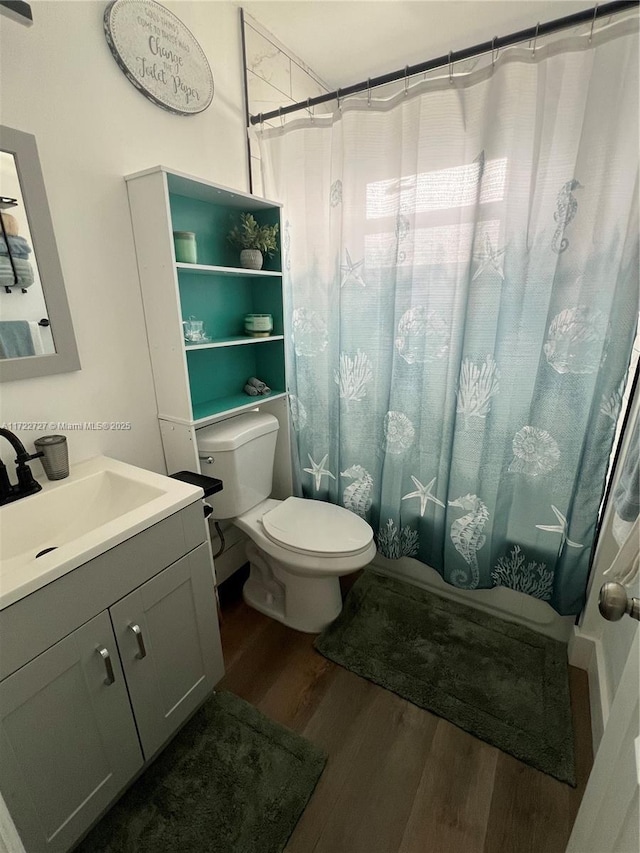 bathroom featuring toilet, shower / bathtub combination with curtain, wood finished floors, and vanity