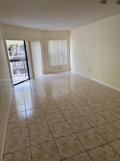 tiled empty room with a textured ceiling