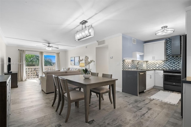 dining room featuring hardwood / wood-style flooring, ceiling fan, ornamental molding, and sink