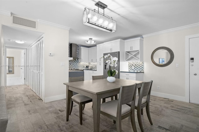 dining area with ornamental molding and light hardwood / wood-style floors