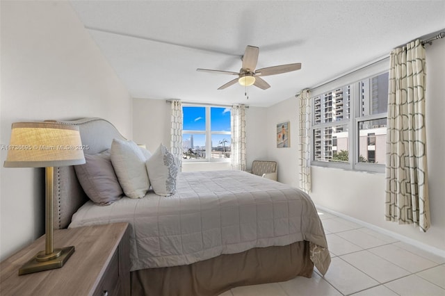 tiled bedroom with ceiling fan and a textured ceiling