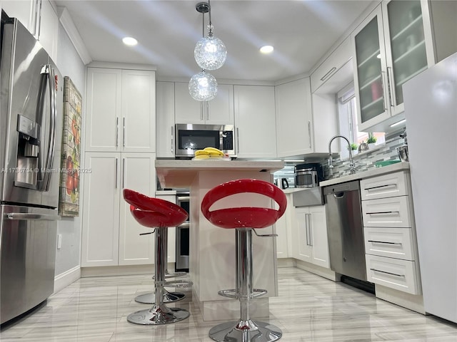 kitchen with white cabinetry, appliances with stainless steel finishes, pendant lighting, and a kitchen breakfast bar