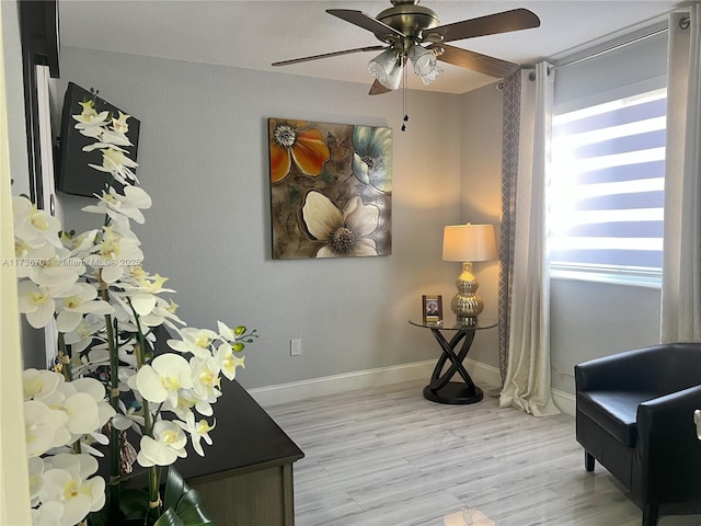 sitting room with ceiling fan and light wood-type flooring