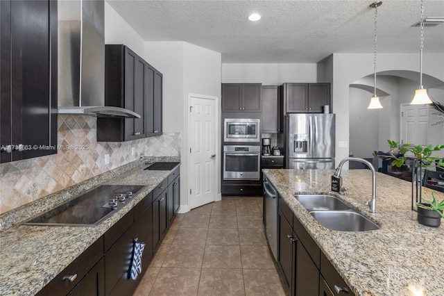 kitchen featuring wall chimney exhaust hood, sink, tasteful backsplash, dark brown cabinets, and stainless steel appliances