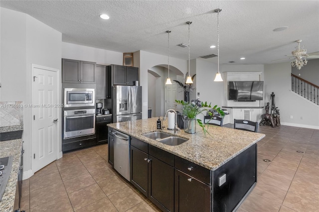 kitchen featuring pendant lighting, sink, appliances with stainless steel finishes, a center island with sink, and light tile patterned flooring